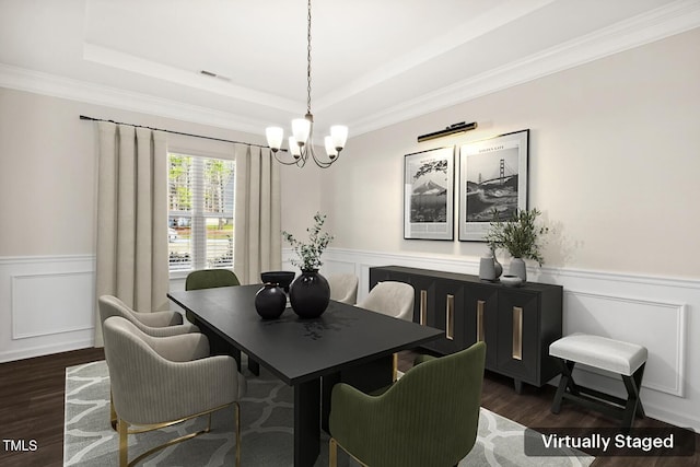 dining space with an inviting chandelier, a wainscoted wall, a tray ceiling, and wood finished floors