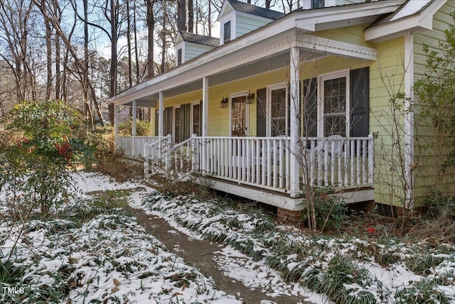 snow covered property with covered porch