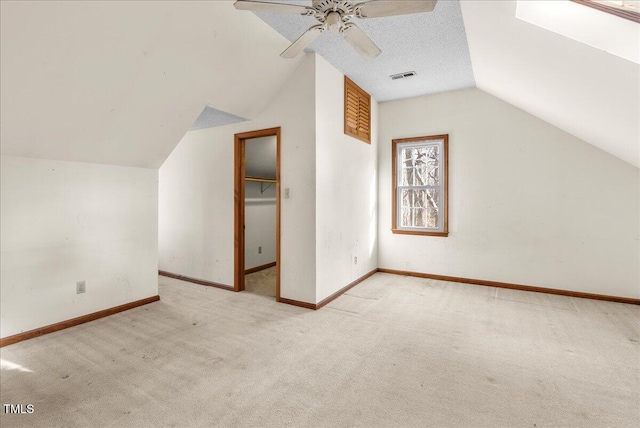 additional living space featuring ceiling fan, vaulted ceiling, light carpet, and a textured ceiling