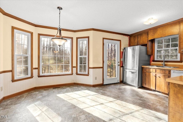 kitchen with stainless steel appliances, ornamental molding, sink, and decorative light fixtures