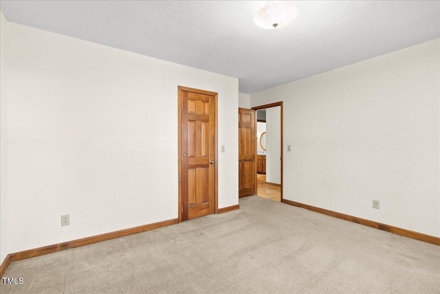 spare room featuring light carpet and a textured ceiling