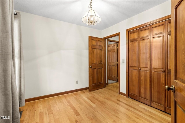 unfurnished bedroom featuring a closet, a notable chandelier, and light hardwood / wood-style flooring