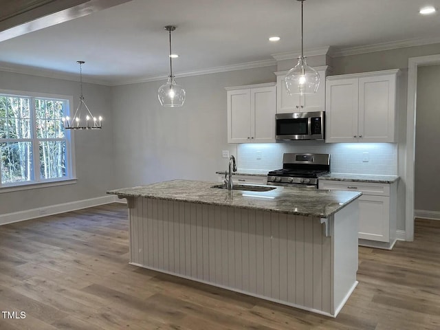 kitchen featuring appliances with stainless steel finishes, white cabinetry, an island with sink, sink, and crown molding