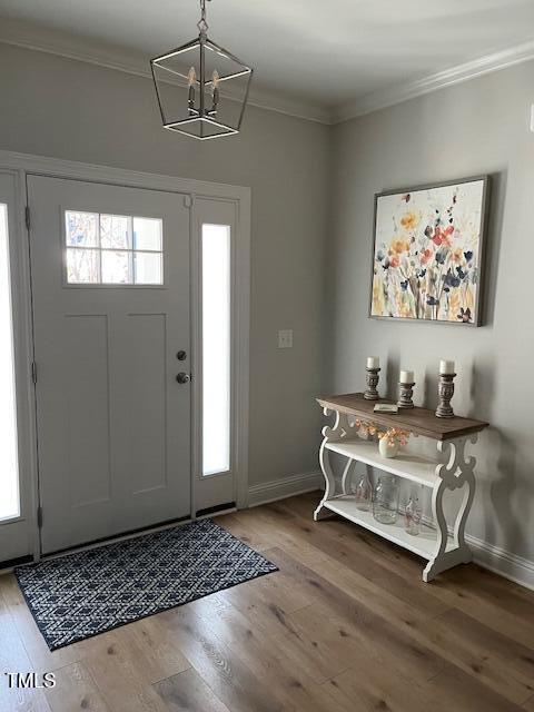 entryway featuring crown molding, hardwood / wood-style floors, and a notable chandelier