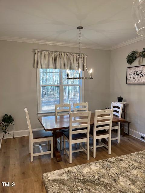 dining area featuring crown molding, dark wood-type flooring, and a notable chandelier