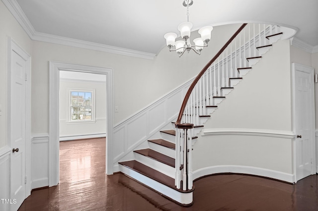 staircase with crown molding, a baseboard heating unit, hardwood / wood-style floors, and an inviting chandelier