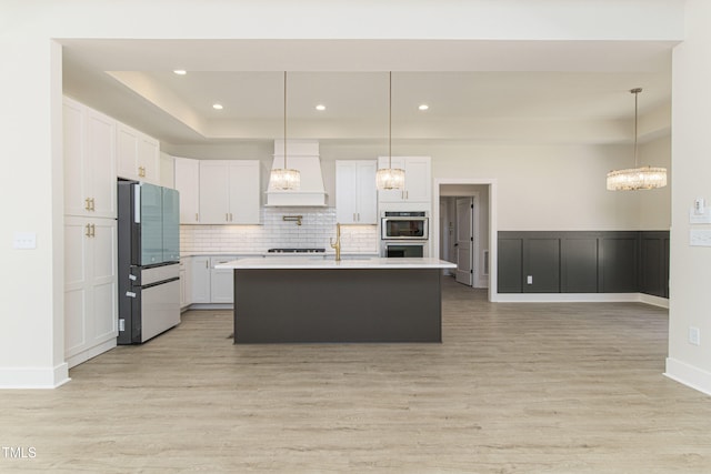 kitchen featuring refrigerator, white cabinetry, hanging light fixtures, double oven, and custom exhaust hood