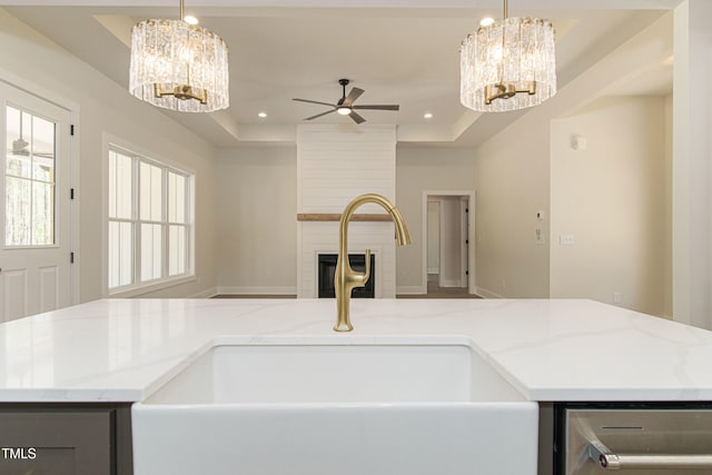 kitchen with a fireplace, decorative light fixtures, a raised ceiling, and sink