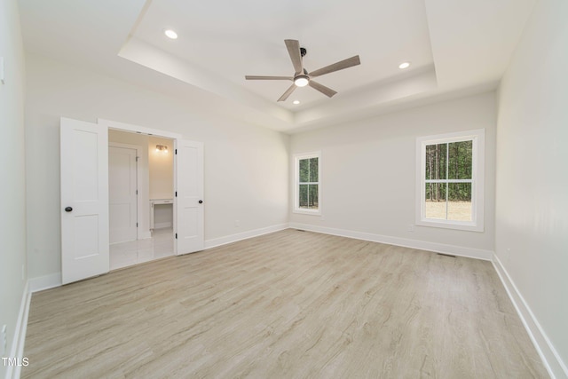 unfurnished bedroom with a raised ceiling, ceiling fan, and light hardwood / wood-style flooring