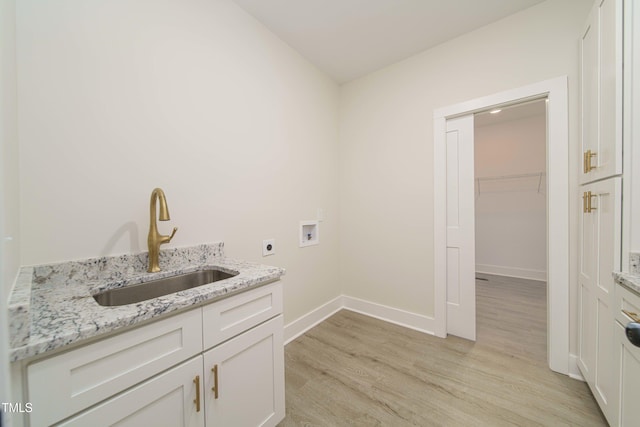 clothes washing area featuring sink, cabinets, washer hookup, hookup for an electric dryer, and light hardwood / wood-style flooring