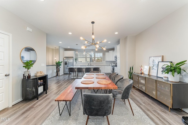 dining area featuring a notable chandelier, sink, and light wood-type flooring