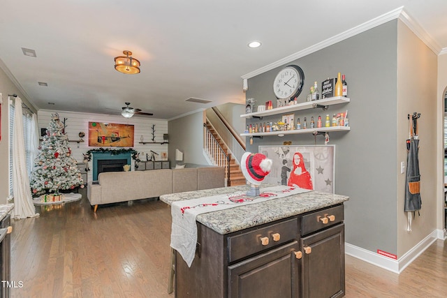 kitchen with dark brown cabinetry, crown molding, light hardwood / wood-style floors, and ceiling fan