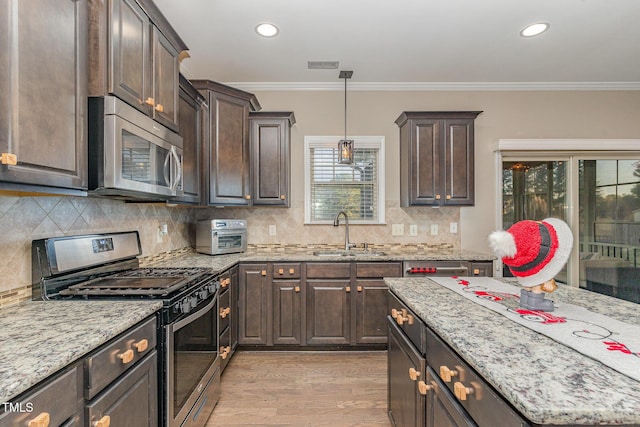 kitchen with sink, crown molding, stainless steel appliances, dark brown cabinetry, and decorative light fixtures