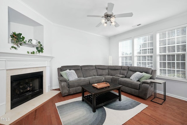 living room with hardwood / wood-style flooring, ornamental molding, a premium fireplace, and ceiling fan