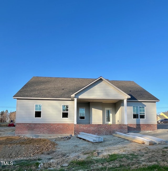 back of property featuring brick siding and roof with shingles