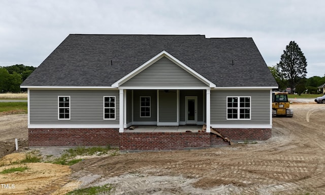 view of front facade with brick siding, a ceiling fan, a porch, and a shingled roof
