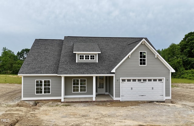 view of front of property with a porch, roof with shingles, and dirt driveway