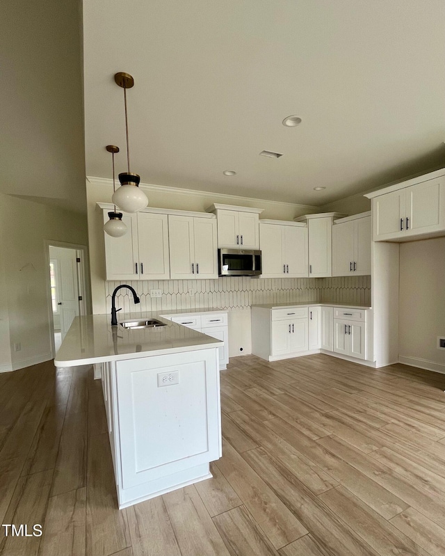 kitchen featuring stainless steel microwave, a sink, tasteful backsplash, white cabinets, and recessed lighting