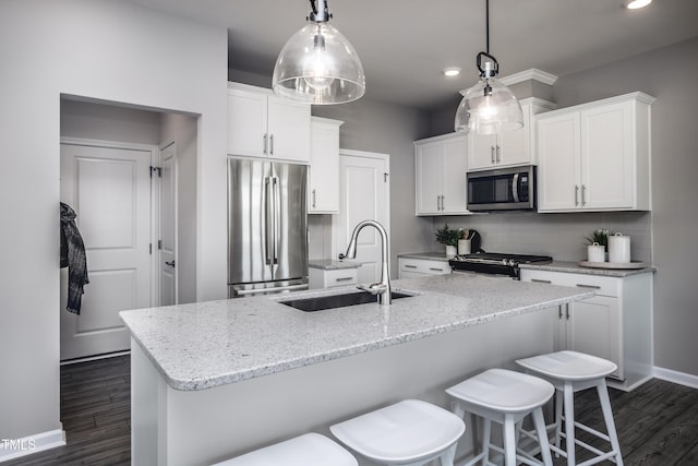 kitchen with pendant lighting, stainless steel appliances, sink, and white cabinets