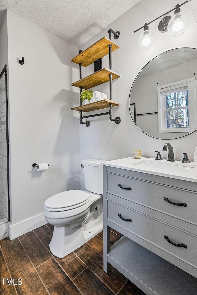 bathroom featuring a textured ceiling, toilet, vanity, and wood tiled floor