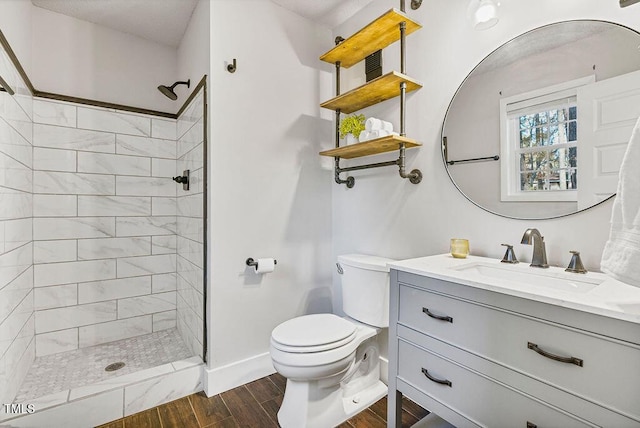 bathroom featuring vanity, tiled shower, and toilet