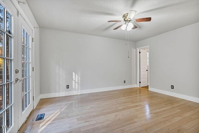 empty room featuring ceiling fan, light hardwood / wood-style flooring, french doors, and a textured ceiling