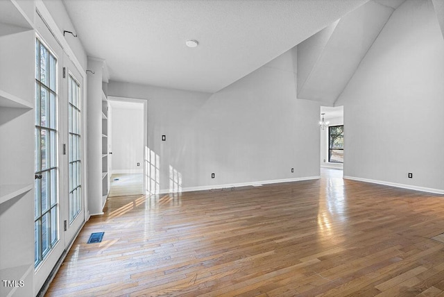 unfurnished living room with lofted ceiling, wood-type flooring, and a chandelier