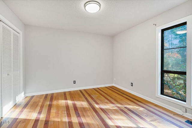 unfurnished bedroom featuring hardwood / wood-style floors, a closet, and a textured ceiling