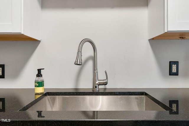 interior details with dark countertops, white cabinets, and a sink