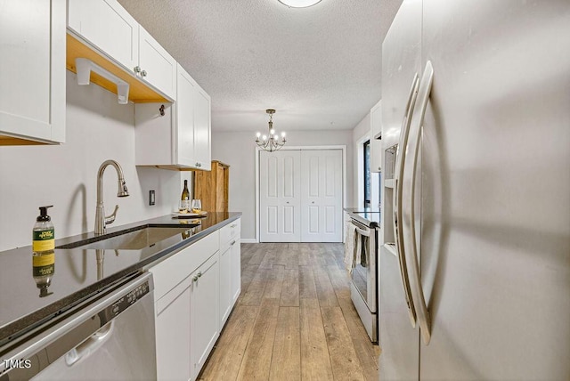 kitchen with electric range, a sink, stainless steel dishwasher, dark countertops, and fridge with ice dispenser