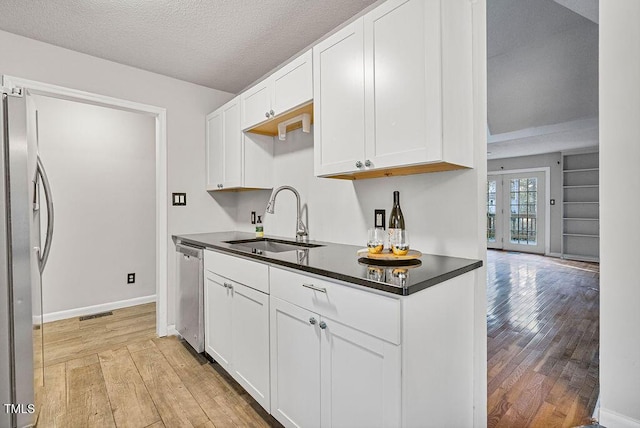 kitchen with white cabinetry, sink, stainless steel appliances, and light hardwood / wood-style floors