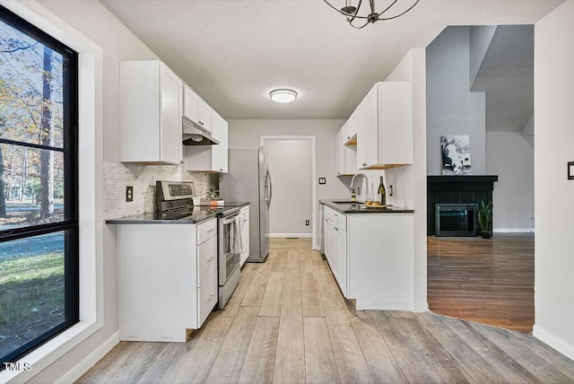 kitchen with stainless steel electric range oven, sink, backsplash, white cabinets, and light wood-type flooring