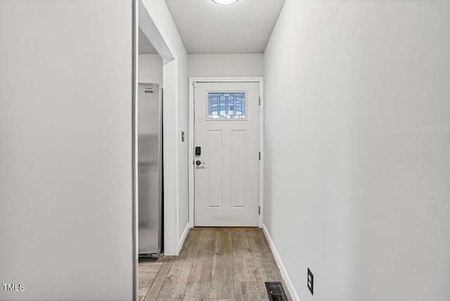 entryway featuring a textured ceiling and light hardwood / wood-style floors