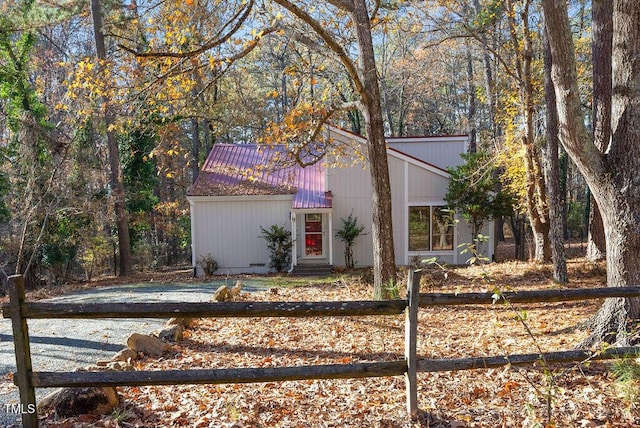 mid-century inspired home featuring a fenced front yard and metal roof