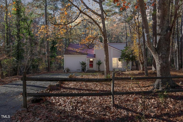 mid-century home featuring fence and a forest view