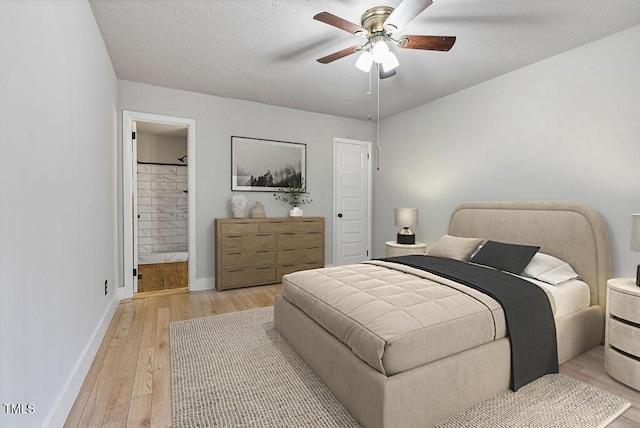 bedroom with baseboards, ceiling fan, light wood-style floors, ensuite bathroom, and a textured ceiling