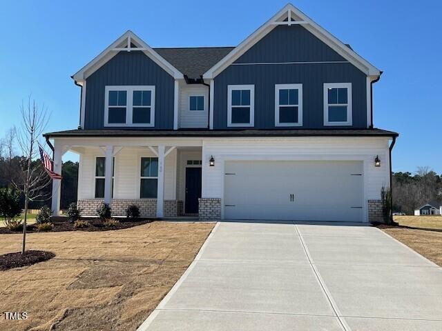 craftsman-style house with driveway, a garage, a porch, board and batten siding, and brick siding