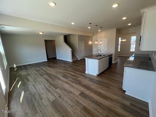 kitchen with dark wood-style floors, a sink, a kitchen island with sink, and white cabinets