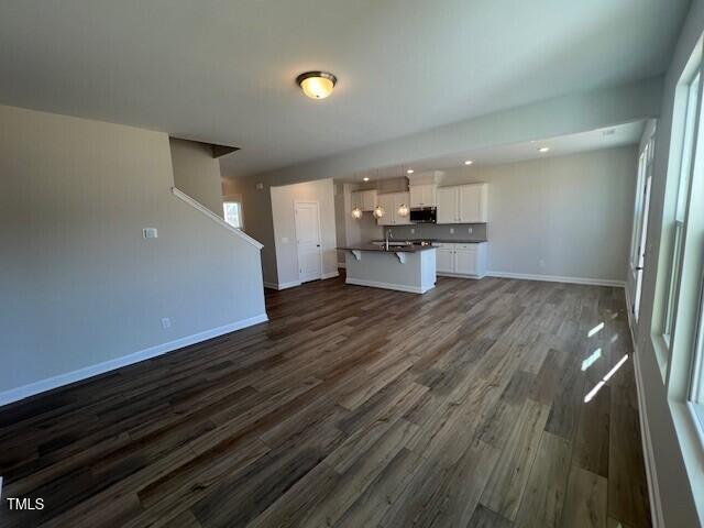 unfurnished living room with dark wood finished floors and baseboards