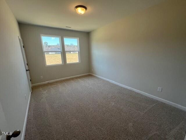 empty room featuring carpet and baseboards