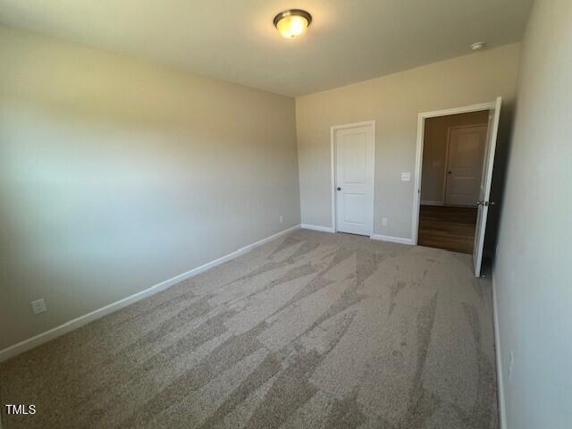 unfurnished bedroom featuring carpet floors and baseboards