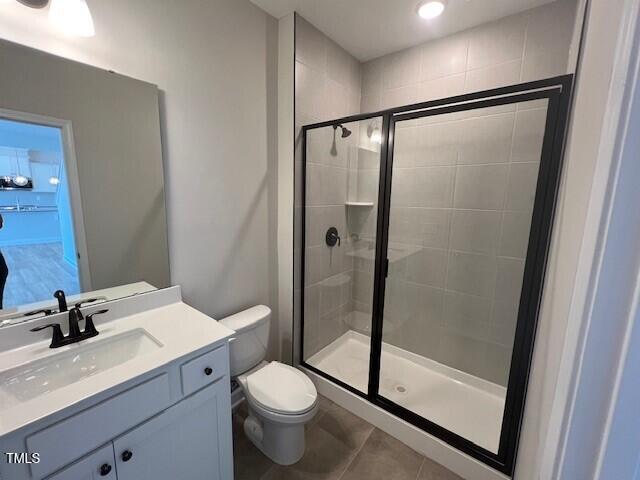 full bathroom with toilet, a stall shower, tile patterned flooring, and vanity