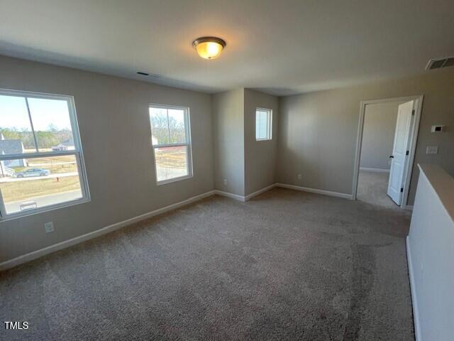 carpeted spare room with plenty of natural light, visible vents, and baseboards