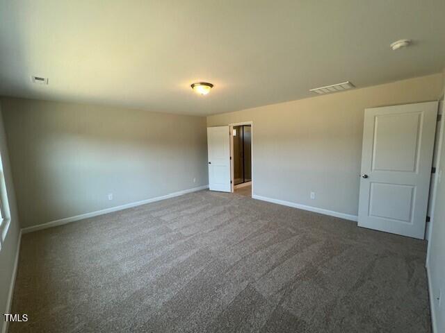 spare room with carpet flooring, visible vents, and baseboards