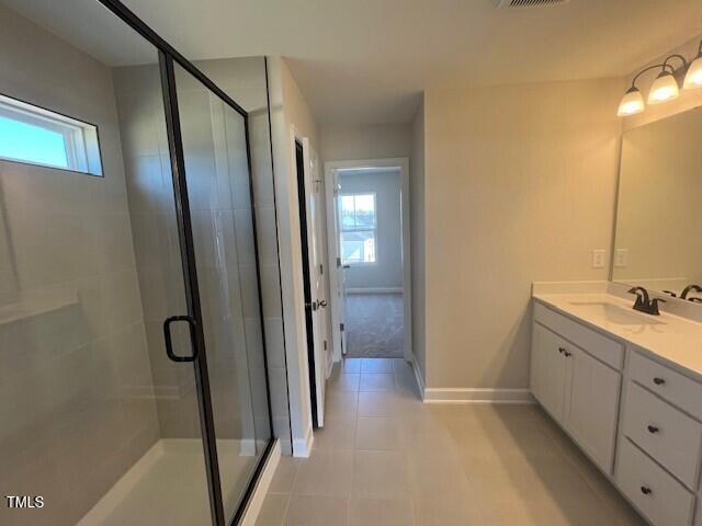 bathroom featuring a shower stall, baseboards, a wealth of natural light, and vanity