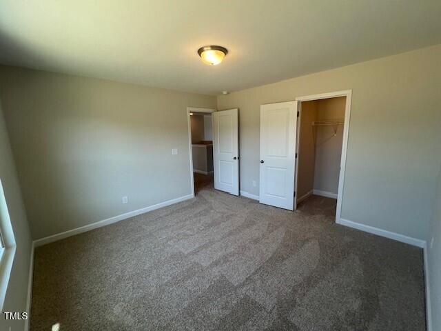 unfurnished bedroom with carpet, a closet, and baseboards