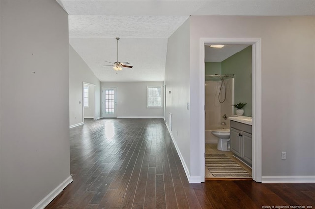 corridor featuring lofted ceiling, a textured ceiling, and dark hardwood / wood-style flooring