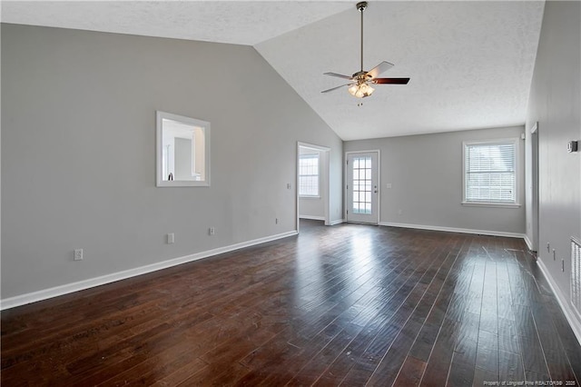 empty room with lofted ceiling, dark hardwood / wood-style floors, a textured ceiling, and ceiling fan