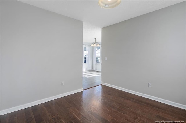 spare room featuring dark hardwood / wood-style floors and an inviting chandelier