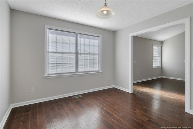 empty room featuring a textured ceiling and dark hardwood / wood-style flooring